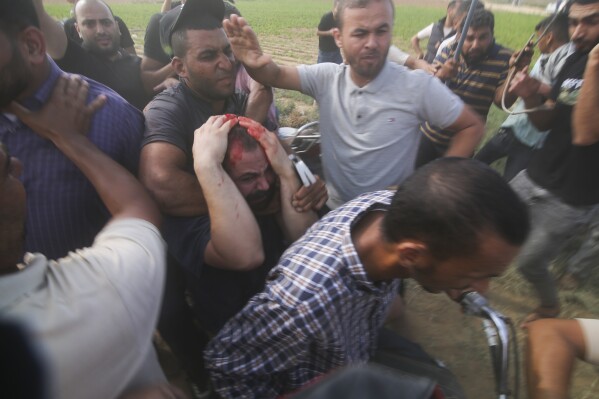 FILE - Palestinians transport a captured Israeli civilian, center, from Kibbutz Kfar Azza into the Gaza Strip on Saturday, Oct. 7, 2023. Israel's military brought together a group of foreign correspondents Monday, Oct. 16, to screen a 40-minute reel of gruesome footage compiled from the Hamas attack last week. The screening came as Israel's military faces increasing pressure to back up their claims of atrocities committed by the militants. (AP Photo, File)