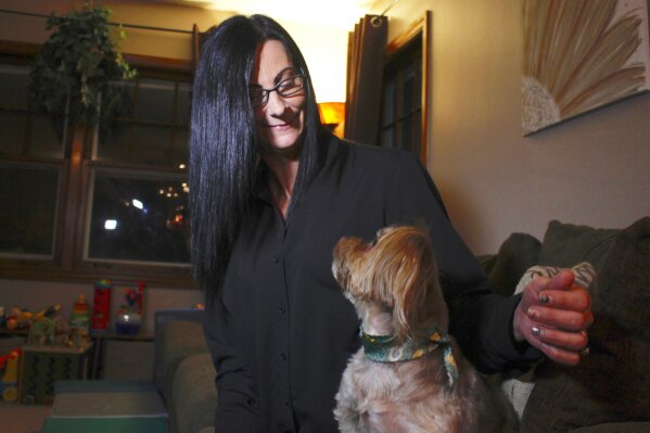 In this Nov. 5, 2019 photo, Amy Carter looks at her dog Bentley at her home in St. Francis, Wis. Carter gives him CBD, which she says has reduced his epilepsy-related seizures. The federal government has yet to establish standards for CBD that will help pet owners know whether it works and how much to give. But the lack of regulation has not stopped some from buying it, fueling a $400 million CBD market for pets that grew more than tenfold since last year and is expected to reach $1.7 billion by 2023, according to the cannabis research firm Brightfield Group. (AP Photo/Carrie Antlfinger)