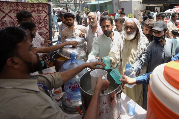 Volunteers provide lime sugar water to people at a camp set up to prevent heat stroke on a hot summer day, in Karachi, Pakistan, Thursday, May 23, 2024. Doctors were treating hundreds of victims of heatstroke at various hospitals across Pakistan on Thursday after an intense spell of the heat wave began in the country, and the mercury rose to above normal due to climate change, officials said. (AP Photo/Fareed Khan)