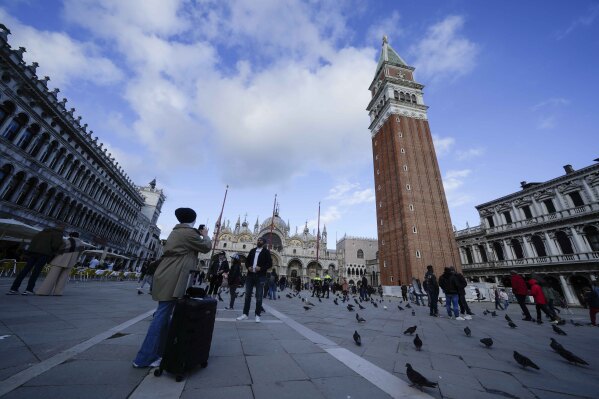 Туристи правят снимки на площад Сан Марко във Венеция, Италия, сряда, 24 април 2024 г. Плажният град Венеция започва пилотна програма в четвъртък, 25 април 2024 г., за да таксува на еднодневните екскурзии входна такса от 5 евро, която властите се надяват обезсърчават туристите.  на пристигане в пиковите дни.  Властите очакват около 10 000 души да платят входни такси в града през първия ден, като изтеглят QR код, за да докажат плащането си.  (AP Photo/Лука Бруно)