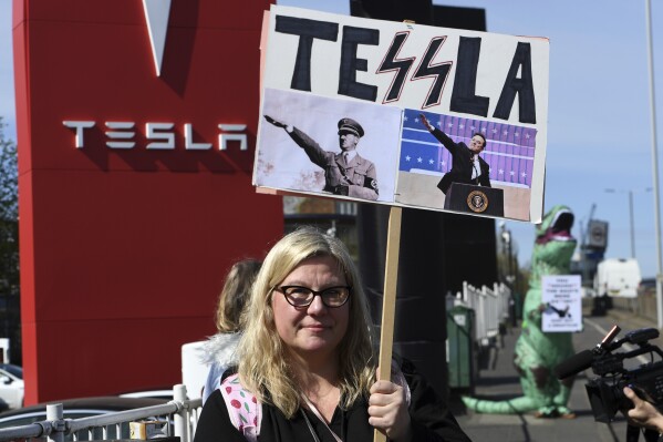 A protester holds a placard as she takes part in the Tesla Takedown Global Day of Action near a Tesla dealership in London, Saturday, March 29, 2025.(AP Photo/Thomas Krych)
