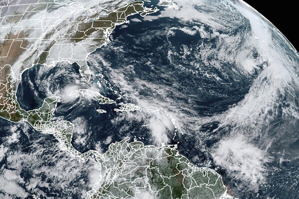 This Tuesday, Nov. 10, 2020, satellite image made available by NOAA shows Tropical Storm Eta at 10:40 a.m. EST in the Gulf of Mexico, Theta, right, and a tropical wave to the south that forecasters say has a good chance of becoming Tropical Storm Iota. (NOAA via AP)