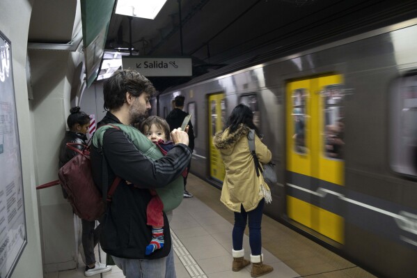 Commuters wait to board a subway car, in Buenos Aires, Argentina, Friday, May 17, 2024. Argentine commuters in Buenos Aires on Friday were hit by an abrupt 360% increase in subway fares, as part of President Javier Milei's budget austerity campaign. (AP Photo/Rodrigo Abd)