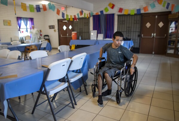Guatemalan migrant Wilson Juarez, 22, helps set tables for lunch at the Pope Francis migrants shelter in El Paso, Texas, on Friday, Aug. 9, 2024. Juarez experienced a brain injury in Ciudad Juarez, Mexico, from smoke inhalation during a prison fire the previous year, which impaired his ability to walk and talk and killed dozens of people. (AP Photo/Andres Leighton)
