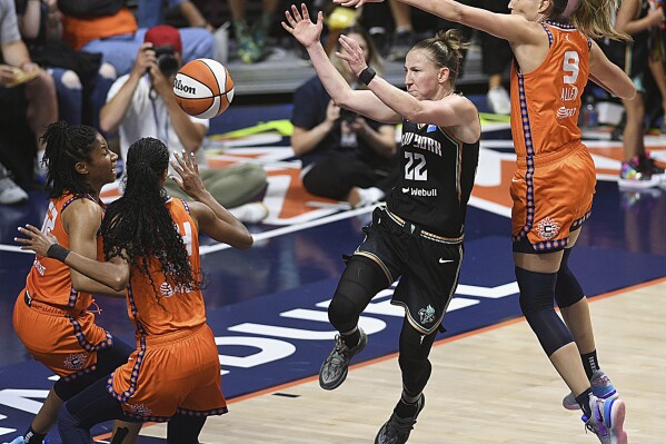 Connecticut Sun's Rebecca Allen (9) attempts to block a pass from New York Liberty's Courtney Vandersloot (22) during a WNBA basketball game Thursday, Aug. 24, 2023, in Uncasville, Conn. (Sarah Gordon/The Day via AP)