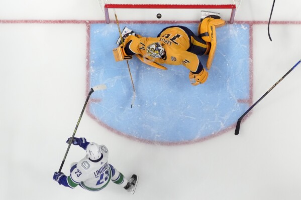 Vancouver Canucks center Elias Lindholm (23) scores a goal past Nashville Predators goaltender Juuse Saros (74) in overtime during Game 4 of an NHL hockey Stanley Cup first-round playoff series Sunday, April 28, 2024, in Nashville, Tenn. The Canucks won 4-3. (AP Photo/George Walker IV)