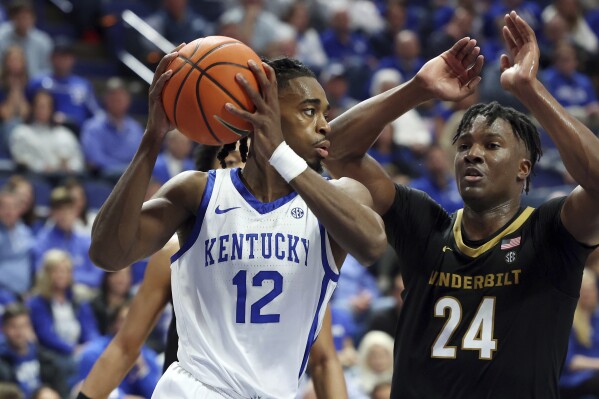 Kentucky's Antonio Reeves (12) is defended by Vanderbilt's JaQualon Roberts (24) during the second half of an NCAA college basketball game Wednesday, March 6, 2024, in Lexington, Ky. (AP Photo/James Crisp)