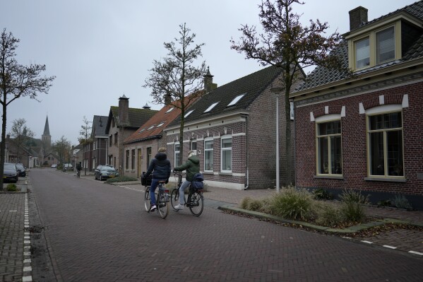 Two boys ride their bikes down a main street in Sprundel, Netherlands, Friday, Dec. 1, 2023. I (AP Photo/Virginia Mayo)