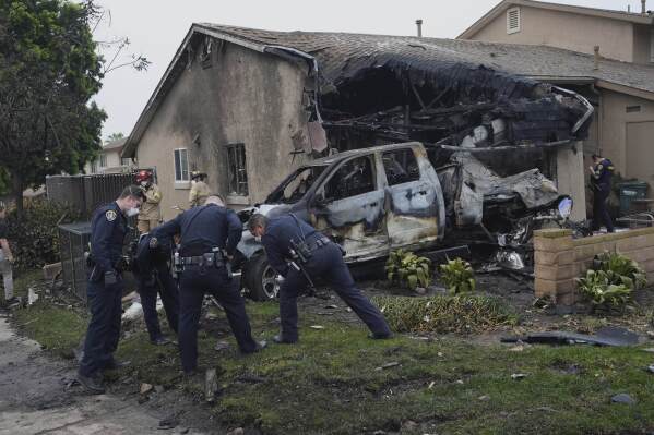 Authorities work the scene where a small plane crashed into a San Diego neighborhood, setting several homes on fire and forcing evacuations along several blocks early Thursday, May 22, 2025. (AP Photo/Gregory Bull)