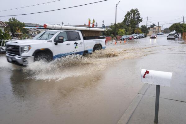A truck drives through a flooded intersection of E Bolivar Street in Salinas, Calif., Tuesday, Dec. 27, 2022. The first in a week of storms brought gusty winds, rain and snow to California on Tuesday, starting in the north and spreading southward. (AP Photo/Nic Coury)