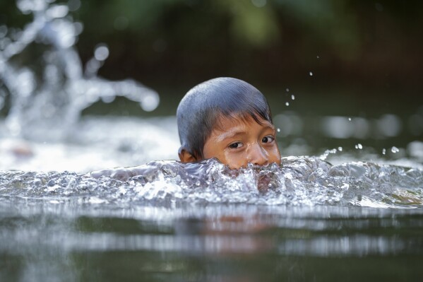 An Indigenous Wari' boy swims in the Komi Memem River, named Laje in non-Indigenous maps, in Guajara-Mirim, Rondonia state, Brazil, Thursday, July 13, 2023. The Amazon city of Guajara-Mirim recently approved a law that designates the river "as a living entity and subject to rights." (AP Photo/Andre Penner)