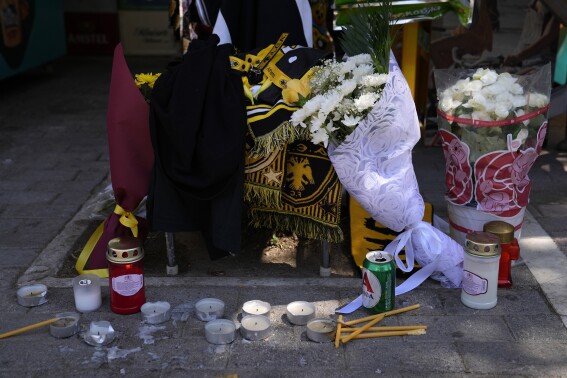 Candles and flowers lie, on the location where a 29-year-old Greek soccer fan has died after overnight clashes between rival supporters in Nea Philadelphia suburb, in Athens, Greece, Tuesday, Aug. 8, 2023. A 29-year-old fan was killed in overnight clashes between rival supporters in the Greek capital, prompting European governing soccer body UEFA to postpone a Champions League qualifying game between AEK Athens and Croatia’s Dinamo Zagreb on Tuesday. (AP Photo/Thanassis Stavrakis)