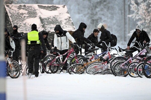 Migrants arrive on bicycles at the Finnish-Russian border crossing in Sala, Finland, Thursday, November 23, 2023. (Jussi Nukari/Lehtikuva via AP)