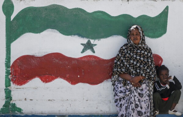 A woman and child relax next to a mural of Somaliland's flag, in Hargeisa, Somaliland, a semi-autonomous breakaway region of Somalia, on Feb. 9, 2022. (AP Photo/Brian Inganga, File)
