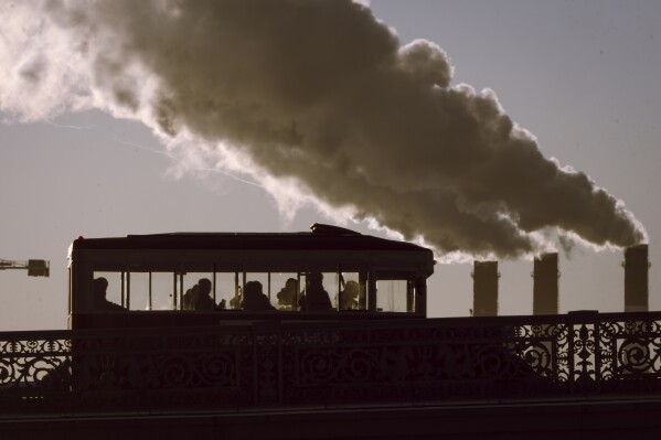 A Soviet-era styled tour bus travels across a bridge past a thermal power plant in St. Petersburg, Russia, Thursday, Feb. 20, 2025. (AP Photo/Dmitri Lovetsky)