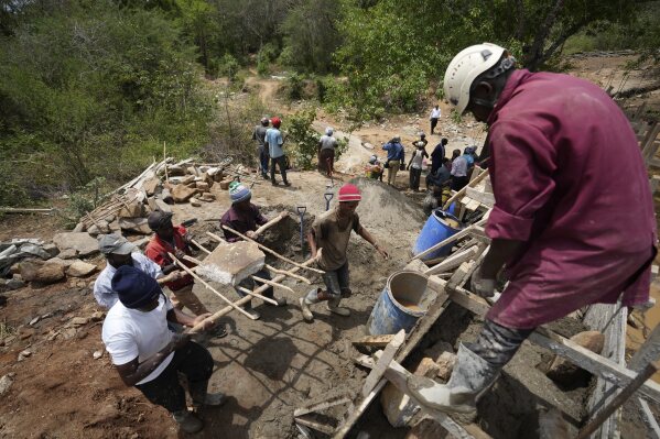 Members of Kyemoo Power, a self-help group, construct a sand dam in Makueni County, Kenya on Thursday, Feb. 29, 2024. Building sand dams, a structure for harvesting water from seasonal rivers, helps minimize water loss through evaporation and recharges groundwater. (AP Photo/Brian Inganga)