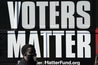 In this Nov. 3, 2020, photo, a man wearing a mask gathers with a group in support of Black Voters Matter at the Graham Civic Center polling site in Graham, N.C. Even as votes are still tallied, there's little dispute that Black voters were a driving national force pushing the former vice president to the winner’s column. (AP Photo/Gerry Broome)