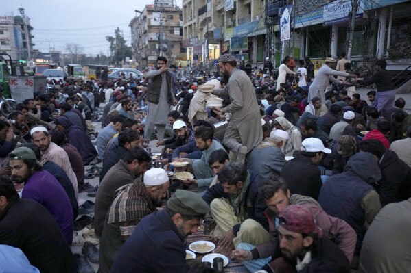 Volunteers distribute food among people for breaking their fast during the Muslim's holy fasting month of Ramadan, at a free meal distribution point, in Rawalpindi, Pakistan, Tuesday, March 12, 2024. (AP Photo/Anjum Naveed)