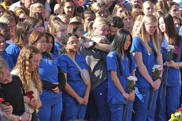 Augusta University students, in blue, and University of Georgia students gather at the Tate Plaza on the UGA campus in Athens, Ga., Monday, Feb. 26, 2024, to pay tribute to Laken Riley, a nursing student at Augusta University's Athens campus who was found dead Thursday, Feb. 22, after a roommate reported she didn't return from a morning run in a wooded area of the UGA campus near its intramural fields. UGA students also gathered to pay tribute to a student who committed suicide last week. (Nell Carroll/Atlanta Journal-Constitution via AP)