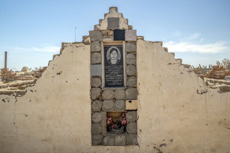 A woman's photo is visible on her grave in a cemetery near the dried-up Aral Sea, on the outskirts of Muynak, Uzbekistan, Monday, June 26, 2023. (AP Photo/Ebrahim Noroozi)