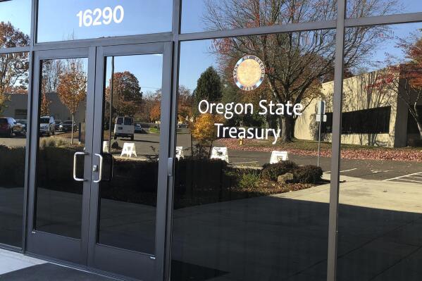 FILE - Nearby buildings are reflected in the windows of the Oregon State Treasury office in Tigard, Ore., on Oct. 30, 2019. A spokeswoman for Oregon State Treasurer Tobias Read said Thursday, Dec. 16, 2021, that Read is looking for clarity in the murky situation surrounding a 2017 investment by the state in a private equity fund called Novalpina Capital, which later acquired a majority share of NSO Group, an Israeli company that produces smartphone spyware and has been blacklisted by the U.S. government. (AP Photo/Andrew Selsky, File)