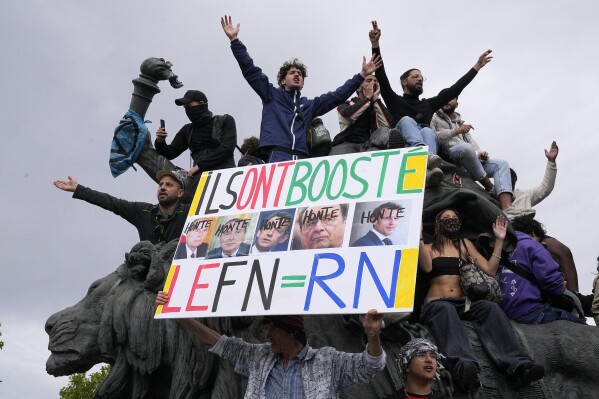 A protester holds an anti-far right banner showing the faces of French Presidents and the word 'Honte' or 'Shame' during a rally in Paris, Saturday, June 15, 2024. Anti-racism groups joined French unions and a brand-new left-wing coalition in protests in Paris and across France on Saturday against the surging nationalist far right as frenzied campaigning is underway ahead of snap parliamentary elections. (AP Photo/Michel Euler)