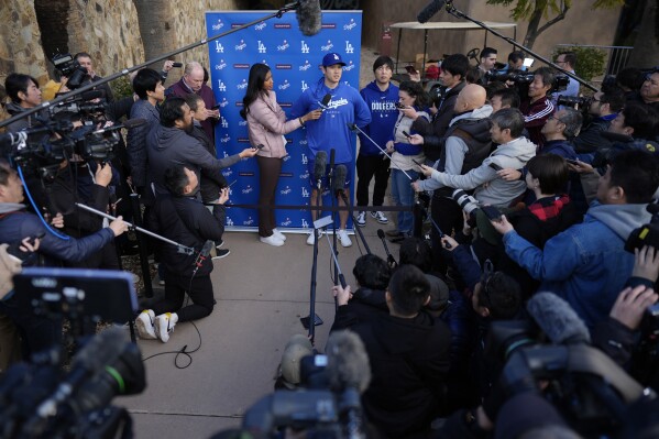 Los Angeles Dodgers' Shohei Ohtani, with interpreter Ippei Mizuhara, right, speaks to media at Camelback Ranch in Phoenix, Friday, Feb. 9, 2024, on the first day of spring training baseball workouts for the Dodgers. (AP Photo/Carolyn Kaster)