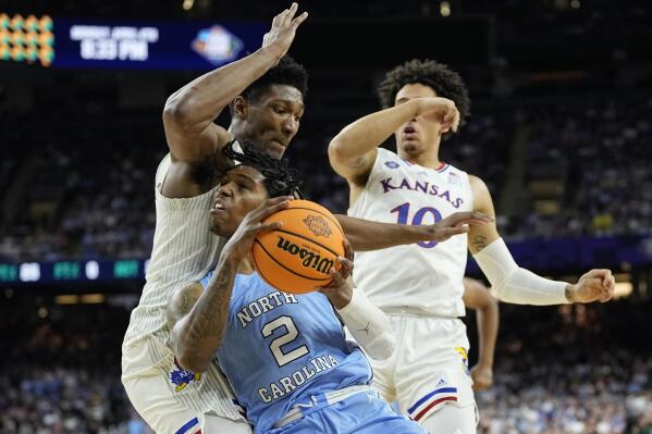 North Carolina guard Caleb Love drives to the basket past Kansas forward David McCormack, left, and forward Jalen Wilson (10) during the first half of a college basketball game in the finals of the Men's Final Four NCAA tournament, Monday, April 4, 2022, in New Orleans. (AP Photo/David J. Phillip)