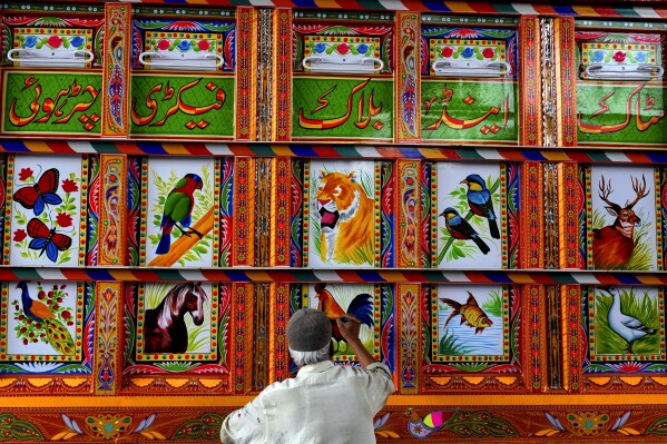 An artisan paints art on a truck at a yard for workshops in Rawalpindi, Pakistan, on Saturday, April 19, 2025. (AP Photo/Anjum Naveed)