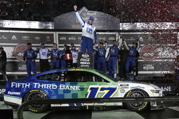 Chris Buescher, center, celebrates in Victory Lane with his crew members after winning a NASCAR Cup Series auto race at Daytona International Speedway, Saturday, Aug. 26, 2023, in Daytona Beach, Fla. (AP Photo/Phelan M. Ebenhack)