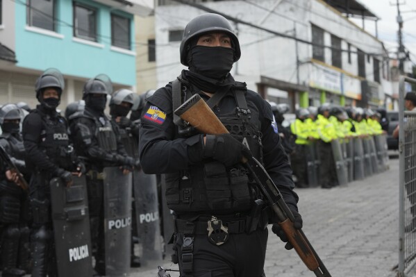 Police and soldiers stand outside El Inca prison after riots began inside in Quito, Ecuador, Monday, Jan. 8, 2024. The riot comes the day after Ecuadorian authorities reported that, at a different prison in the city of Guayaquil, Los Choneros gang leader Adolfo Macías, alias “Fito,” was not in his cell. A decade ago, he fled from another facility. (AP Photo/Dolores Ochoa)