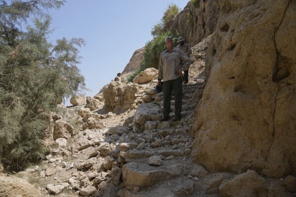 Inspectors from Israel's Nature and Parks Authority assess the site of a rockslide, with the loose stones seen at left, that took place in the Ein Gedi Nature Reserve, on the western shore of the Dead Sea, a popular tourist site in Israel, Thursday, Aug. 24, 2023. An avalanche of rock tumbled down a hillside near the Dead Sea, Israeli medics said, injuring several people, including children. (AP Photo/Ohad Zwigenberg)