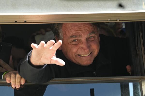 Brazil's former President Jair Bolsonaro waves to supporters at the Liberal Party's headquarters in Brasilia, Brazil, Thursday, March 30, 2023. Bolsonaro arrived back in Brazil on Thursday after a three-month stay in Florida, seeking a new role on the political scene. (AP Photo/Eraldo Peres)