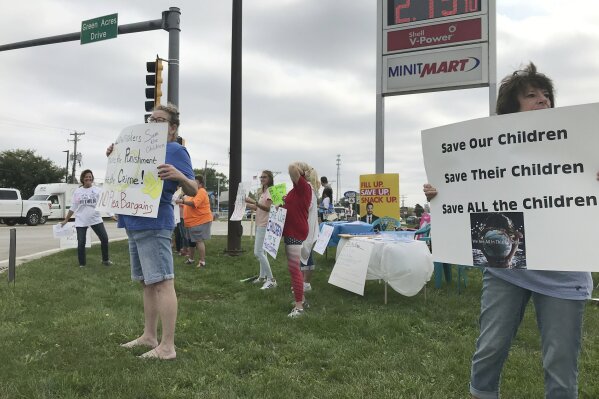 A group holds signs rallying in support of the “Save the Children” movement, calling for an end to child trafficking Sept. 26, 2020, in Morris, Ill. Conversations about “Save the Children” have spiked on social media in recent months and some supporters have taken to city and suburban streets across the U.S. to promote their new cause. Their catchphrase was first made popular online by conspiracy theorists promoting QAnon. (AP Photo/Amanda Seitz)