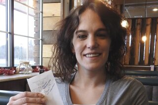 In this Dec. 30, 2019 photo, server Danielle Franzoni holds a receipt from a customer with a $2,020 tip included at Thunder Bay River Restaurant in Alpena, Mich. The credit card receipt said "Happy New Year. 2020 Tip Challenge." Franzoni, a single mother, couldn't believe the number, but her manager assured her the tip was legitimate. She said she was living in a homeless shelter a year ago. Franzoni plans to use the money to reinstate her driver's license and build savings. (Julie Riddle/The News via AP)