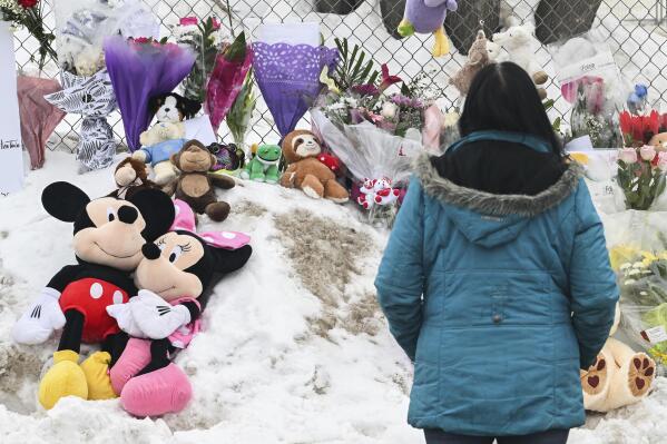 A woman stands next to a memorial at the site of a daycare centre in Laval, Quebec, Thursday, Feb. 9, 2023, where a bus crashed into the building killing two children. (Graham Hughes/The Canadian Press via AP)