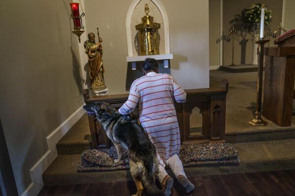 Tanya Britton prays with her dog, Sybil, by her side, while helping to prepare for Mass at St. James Catholic Church in Tupelo, Miss., Tuesday, May 24, 2022. Many people across the U.S. are reacting with horror to the Supreme Court's abortion decision, overturning Roe v. Wade. But on a day that belonged to the victors, millions of others like Britton, who've been immersed in the anti-abortion movement for the past half-century, are rejoicing. (AP Photo/David Goldman)