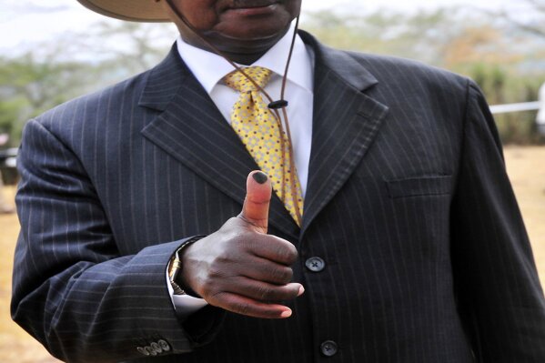 FILE - In this Friday Feb. 18, 2011 file photo, Uganda's President Yoweri Museveni shows the ink mark on the thumb after he voted in Kiruhura district which is Museveni's home area, Uganda, Deadly violence and repressive measures have alarmed observers as Uganda prepares to vote on Jan. 14, 2021, with longtime President Yoweri Museveni challenged by young singer and lawmaker Bobi Wine, who has captured the imagination of many across Africa in a generational clash. (AP Photo/Ronald Kabuubi, file)