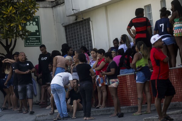 People wait outside the Getulio Vargas Hospital for the arrival of victims of a police raid that killed at least 9 people in the Vila Cruziero favela, in Rio de Janeiro, Brazil, Wednesday, Aug. 2, 2023. Police said the raid targeted criminal gangs in Rio's favela. (AP Photo/Bruna Prado)