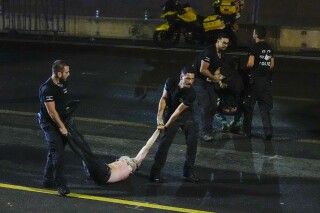 An injured demonstrator is dragged by police to be detained during a protest against plans by Netanyahu's government to overhaul the judicial system, in Tel Aviv, Israel, Monday, July 24, 2023. Israeli lawmakers on Monday approved a key portion of Prime Minister Benjamin Netanyahu's divisive plan to reshape the country's justice system despite massive protests that have exposed unprecedented fissures in Israeli society. (AP Photo/Ariel Schalit)