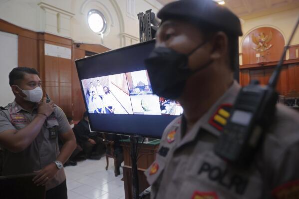 Police officers stand near a monitor inside a court room during a trial in Surabaya, East Java, Indonesia , Monday, Jan, 16, 2023. The court began a trial Monday against five men on charges of negligence leading to deaths of 135 people after police fired tear gas inside a soccer stadium, setting off a panicked run for the exits in which many were crushed. (AP Photo/Trisnadi)