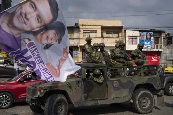 Soldiers stand guard on top of an armored vehicle as supporters of presidential candidate Daniel Noboa, of the National Democratic Action Alliance political party, attend a rally downtown in Esmeraldas, Ecuador, Friday, Oct. 6, 2023. Ecuador will hold a presidential runoff, Oct. 15. (AP Photo/Rodrigo Abd)