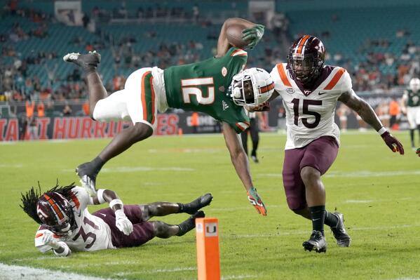 Miami wide receiver Brashard Smith (12) runs for a first down over Virginia Tech defensive back Nasir Peoples (31) and Virginia Tech linebacker Keshon Artis (15) during the first half of an NCAA college football game, Saturday, Nov. 20, 2021, in Miami Gardens, Fla. (AP Photo/Lynne Sladky)