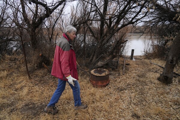 Gayna Salinas walks along her property bordering the Green River, a tributary of the Colorado River, Thursday, Jan. 25, 2024, in Green River, Utah. An Australian company and its U.S. subsidiaries are eyeing a nearby area to extract lithium. Salinas, whose family farms in the rural community, said she was skeptical about the project's benefits. (AP Photo/Brittany Peterson)