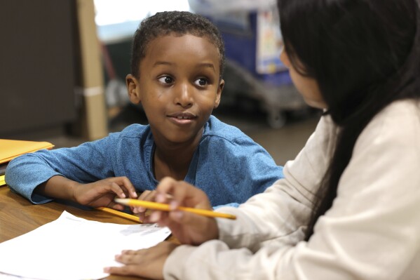 Ayub Mohamed, left, 7, going into 2nd grade, gets help from Esmeralda Jimenez, 13, a volunteer tutor in a summer tutoring program with School Connect WA at Dearborn Park International Elementary School in Seattle on Friday, July 28, 2023. (Karen Ducey/The Seattle Times via AP)