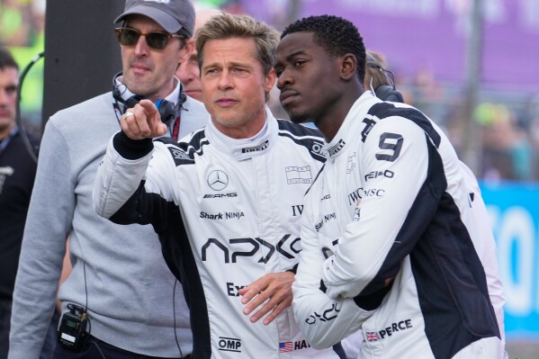 Actors Brad Pitt, left, and Damson Idris appear on the grid before the British Formula One Grand Prix race at the Silverstone racetrack, Silverstone, England, on July 9, 2023, for the filming of 