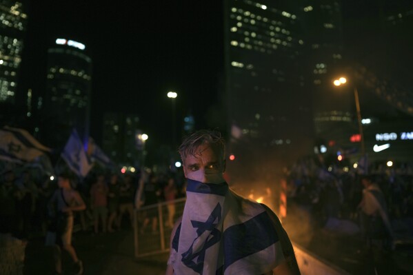 Demonstrators protest against plans by Prime Minister Benjamin Netanyahu's government to overhaul the judicial system, in Tel Aviv, Monday, July 24, 2023. Israeli lawmakers on Monday approved a key portion of Prime Minister Benjamin Netanyahu's divisive plan to reshape the country's justice system despite massive protests that have exposed unprecedented fissures in Israeli society. (AP Photo/Oded Balilty)