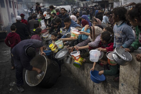 Palästinenser stehen am Donnerstag, 21. Dezember 2023, in Rafah im Gazastreifen Schlange, um kostenloses Essen zu erhalten.  Internationale Hilfsorganisationen sagen, dass Gaza infolge des zweieinhalbmonatigen Krieges unter einem Mangel an Nahrungsmitteln, Medikamenten und anderen Grundgütern gelitten habe.  Israel und Hamas.  (AP Photo/Fatima Shpir)