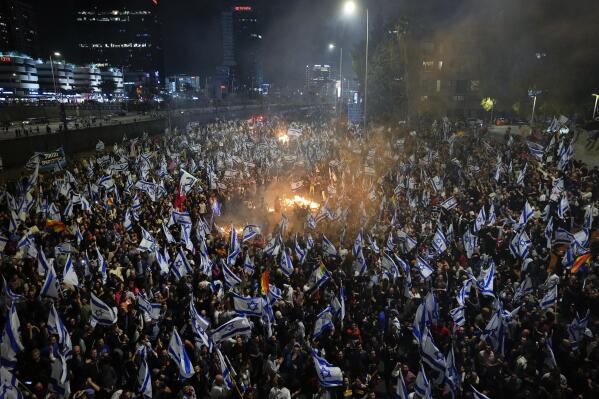FILE - Israelis opposed to Prime Minister Benjamin Netanyahu's judicial overhaul plan set up bonfires and block a highway during a protest moments after the Israeli leader fired his defense minister, in Tel Aviv, Israel, Sunday, March 26, 2023. Netanyahu's corruption trial has resumed after a month-long break. The resumption refocuses the spotlight on the long-serving leader's legal woes after a wave of protests over his government's plan to overhaul the country's judiciary. (AP Photo/Ohad Zwigenberg, File)