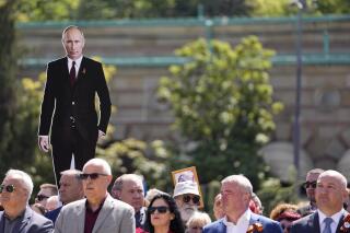 Un hombre sostiene una fotografía del presidente ruso Vladimir Putin durante la ceremonia del Día de la Victoria en Belgrado, Serbia, el lunes 9 de mayo de 2022. (AP Foto/Darko Vojinovic)